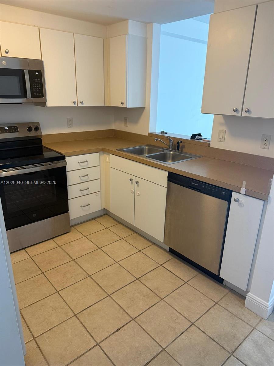 A kitchen features white cabinets, stainless steel appliances, a double sink, and tiled flooring — 1250 S Miami Ave # 1412, Miami FL 33130, MIAMI, FL