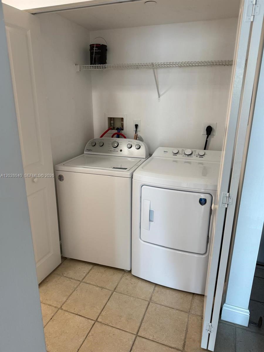 A laundry closet features a white top-load washer and dryer with tile flooring — 1250 S Miami Ave # 1412, Miami FL 33130, MIAMI, FL
