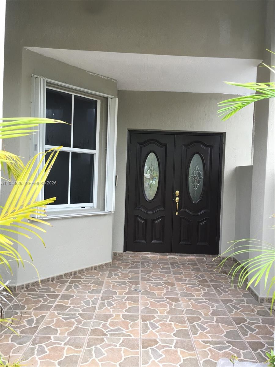 A covered entryway features a tiled floor, a window with shutters, and double front doors — 15431 SW 39th Ter, Miami FL 33185, MIAMI, FL