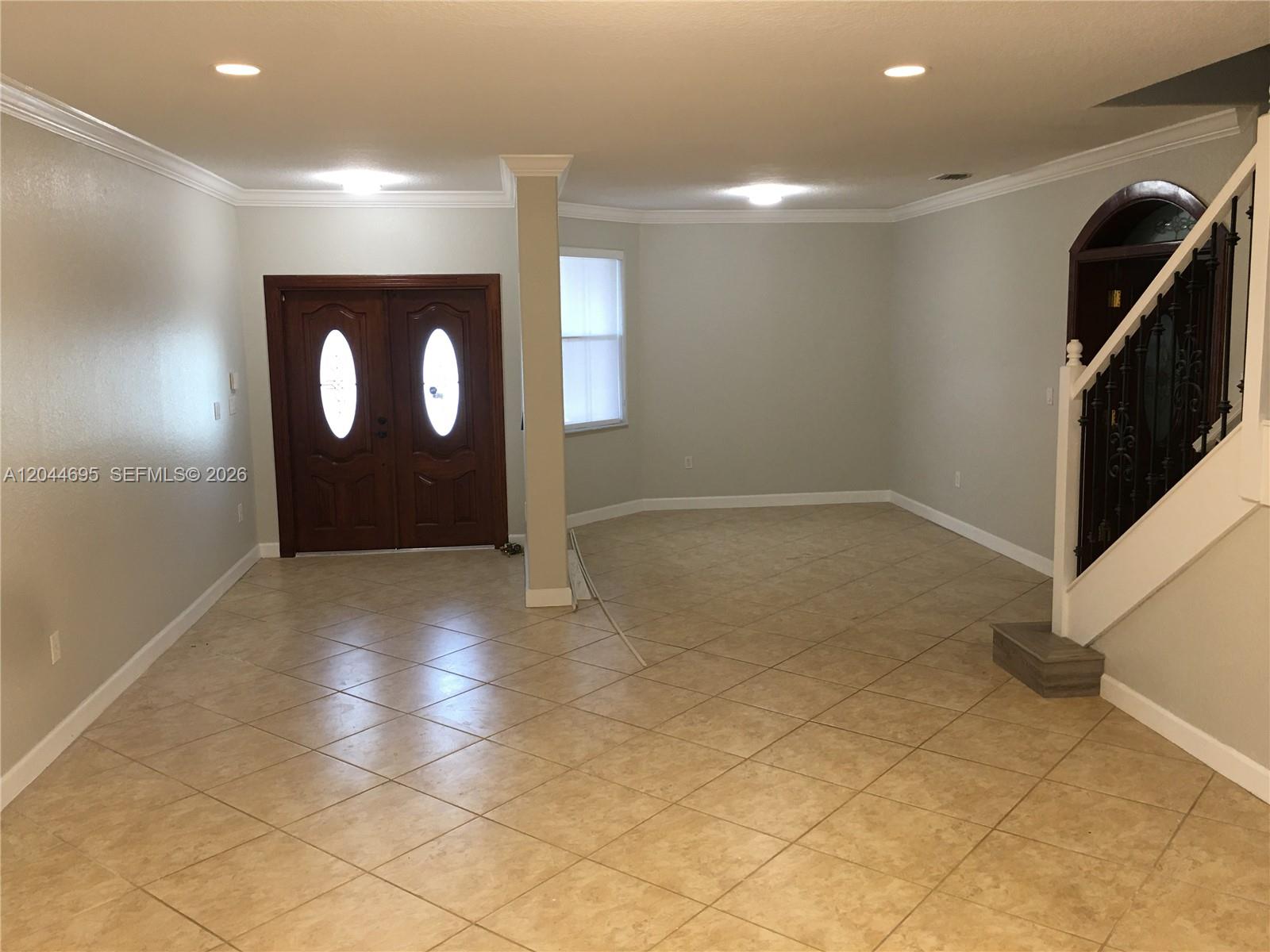 An entryway features tile flooring, a wooden double door, and a staircase with iron railings — 15431 SW 39th Ter, Miami FL 33185, MIAMI, FL