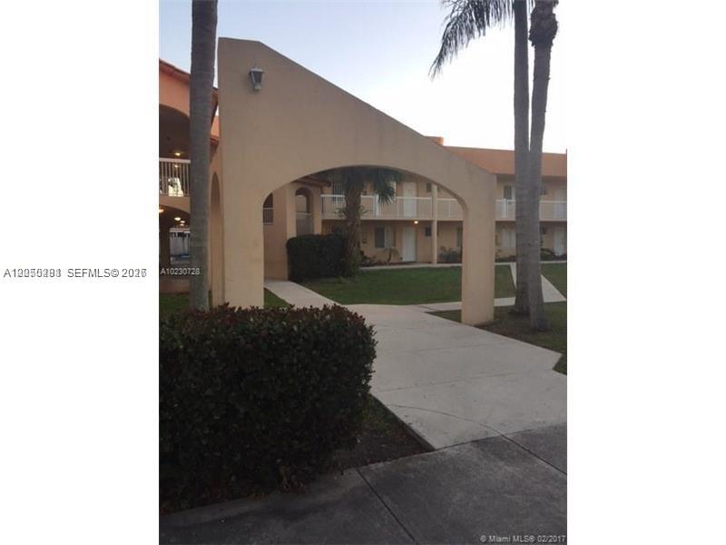 An arched stucco entryway stands before a multi-story apartment building with palm trees — 2390 W 74th St # 202, Hialeah FL 33016, HIALEAH, FL