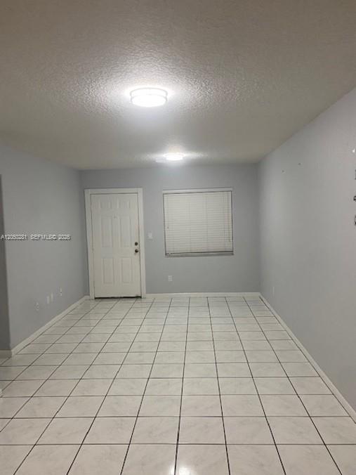 An empty room with light gray walls, white tile flooring, and two ceiling light fixtures — 2390 W 74th St # 202, Hialeah FL 33016, HIALEAH, FL