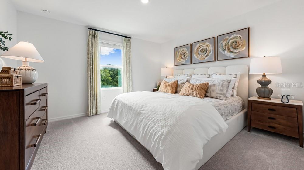 A bedroom features a white bed, two wooden nightstands, a dresser, and three floral wall paintings — 2691 BALMERINO WAY, MOUNT DORA, FL