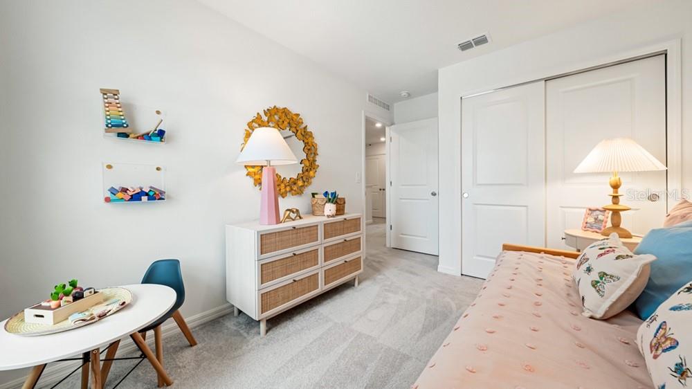 A bedroom features a white dresser, a small table with a chair, and a bed — 2691 BALMERINO WAY, MOUNT DORA, FL