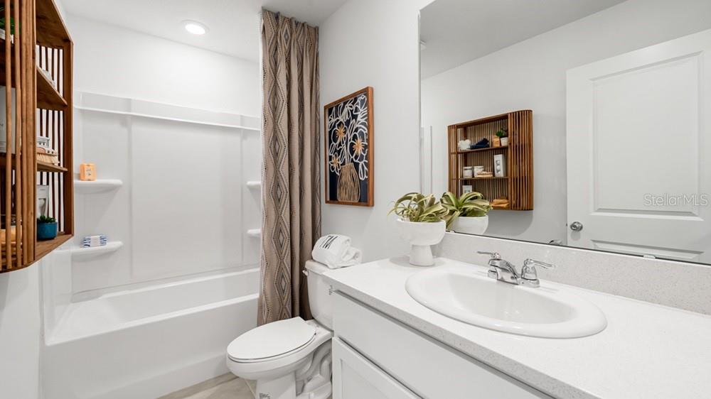 A bathroom features a white vanity, a toilet, and a shower-tub combination with a curtain — 2691 BALMERINO WAY, MOUNT DORA, FL