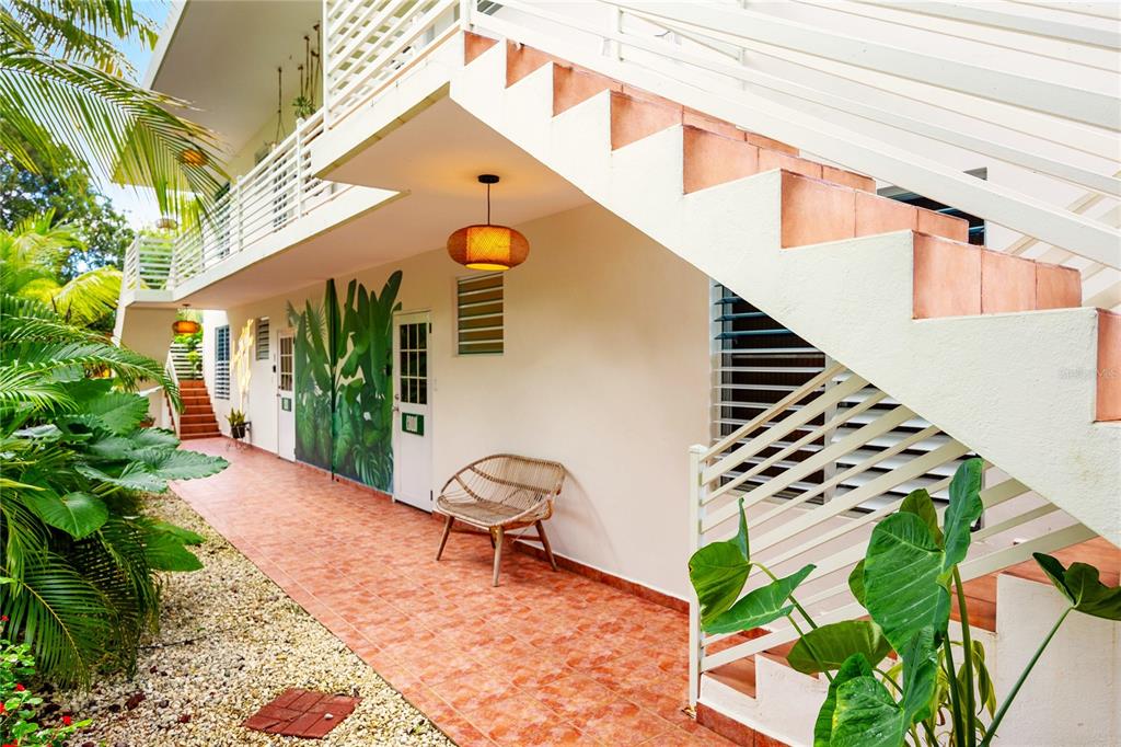 A covered outdoor walkway features tiled flooring, a rattan chair, and an exterior staircase — Carr. 413 Int.  Km 4 THE JUNGLE, RINCON, PR