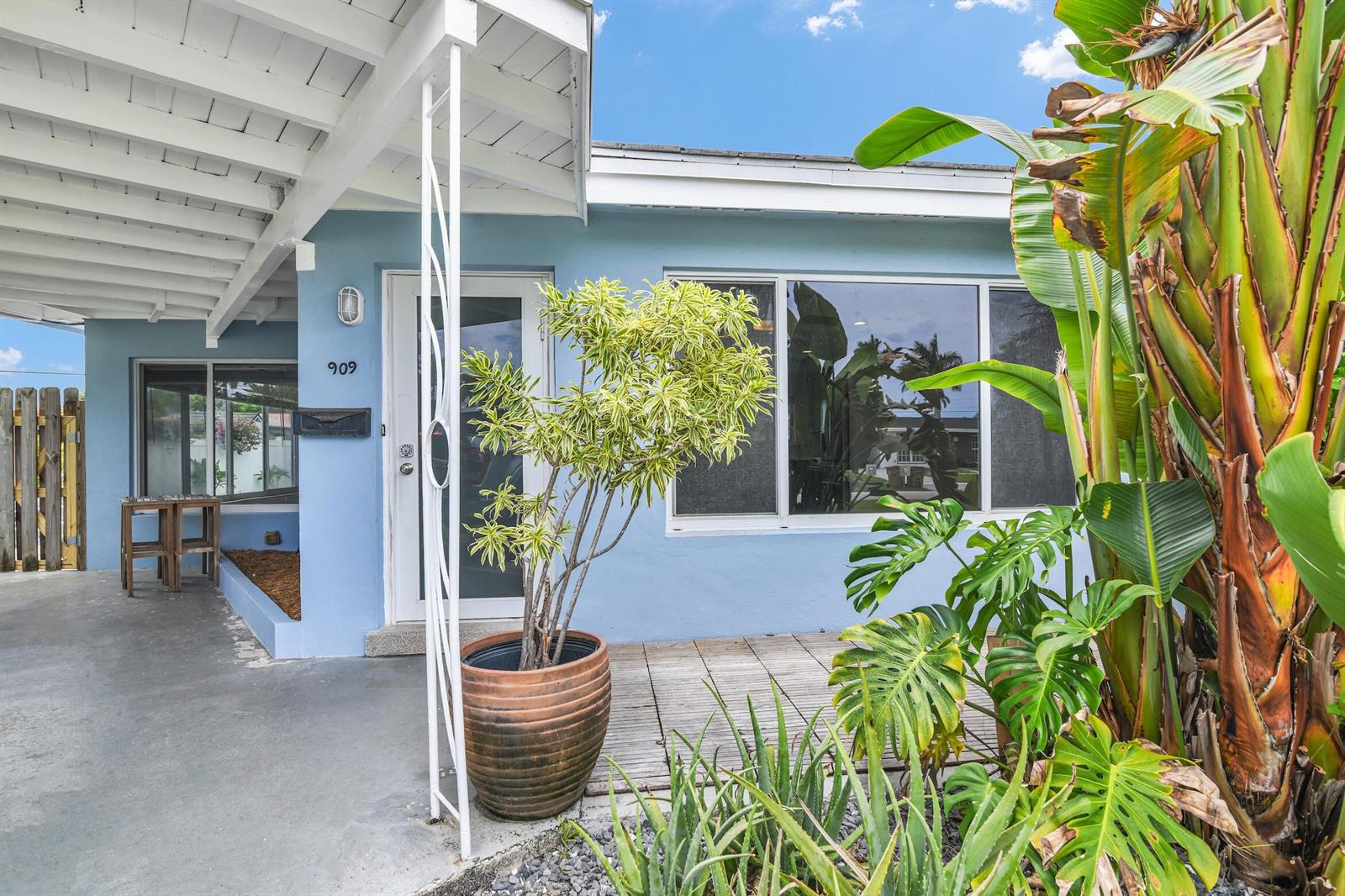 The exterior of a light blue house features a covered porch, large windows, and plants — 909 SE 16 Place, Deerfield Beach FL 33441, DEERFIELD BEACH, FL