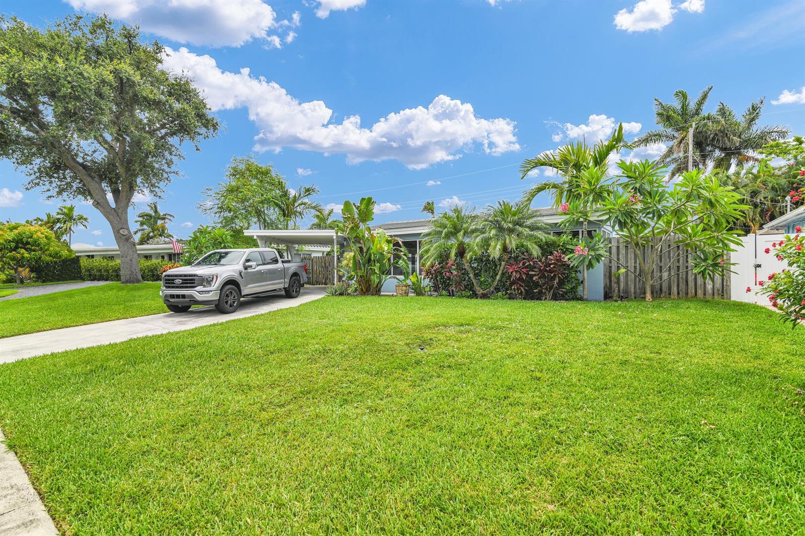A silver pickup truck is parked in the driveway of a single-story house with landscaping — 909 SE 16 Place, Deerfield Beach FL 33441, DEERFIELD BEACH, FL