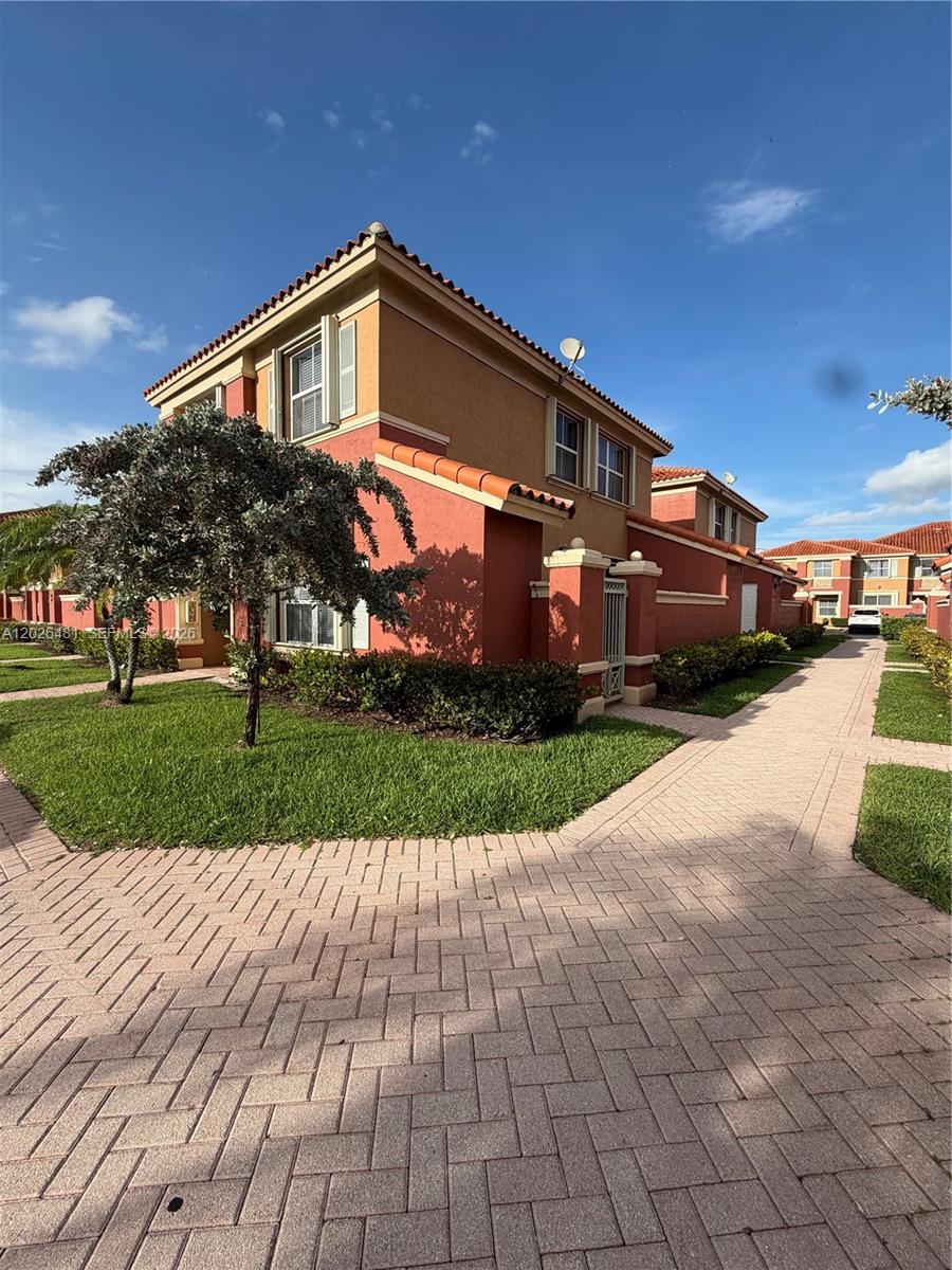 A two-story stucco townhouse with a red exterior and a paved walkway — 6202 NW 115th Pl # 336, Doral FL 33178, DORAL, FL