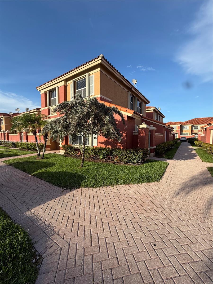 A two-story residential building with a red and tan exterior sits beside a brick walkway — 6202 NW 115th Pl # 336, Doral FL 33178, DORAL, FL