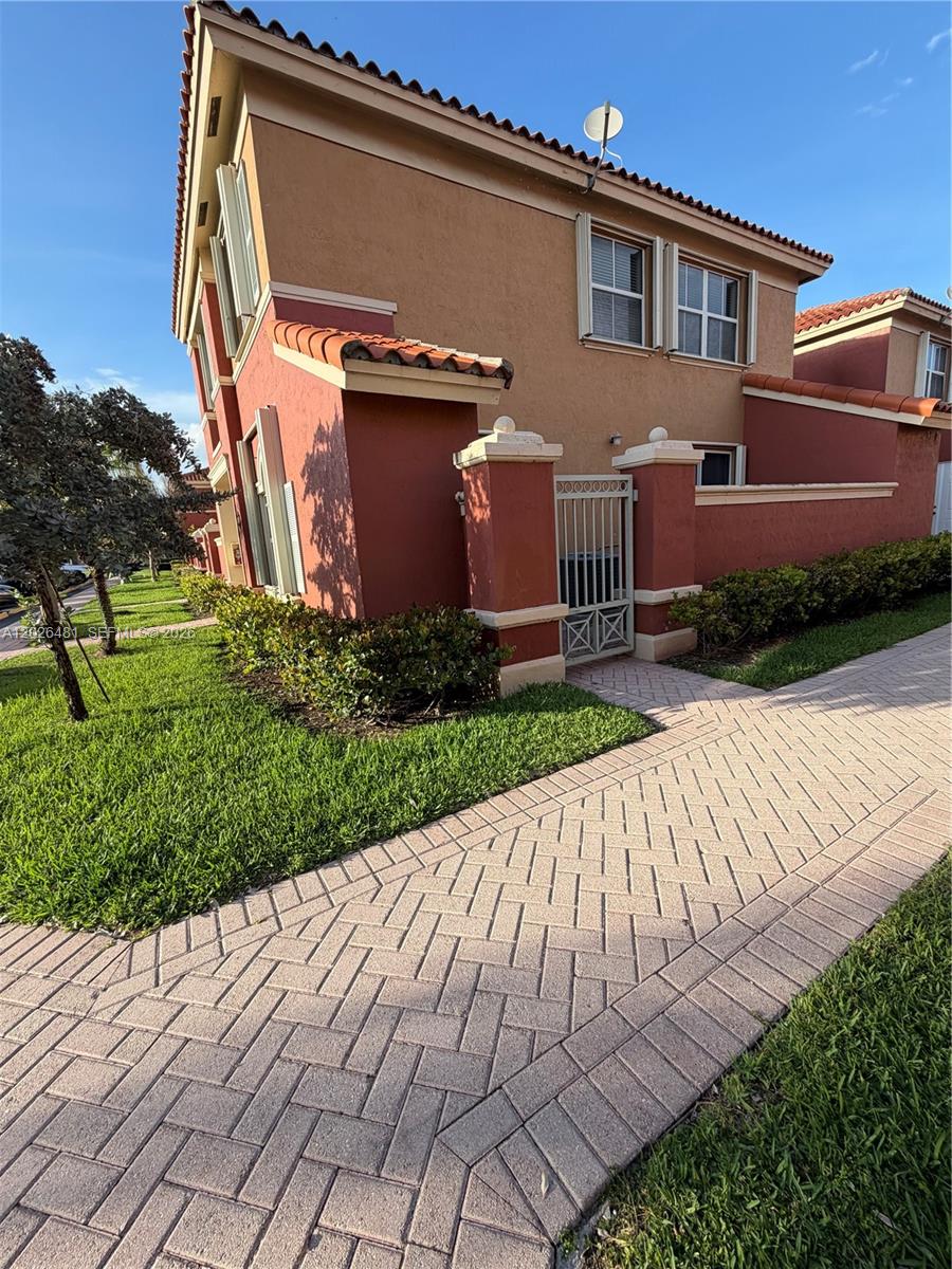 A two-story stucco townhouse features a gated side entrance and a brick paver walkway — 6202 NW 115th Pl # 336, Doral FL 33178, DORAL, FL