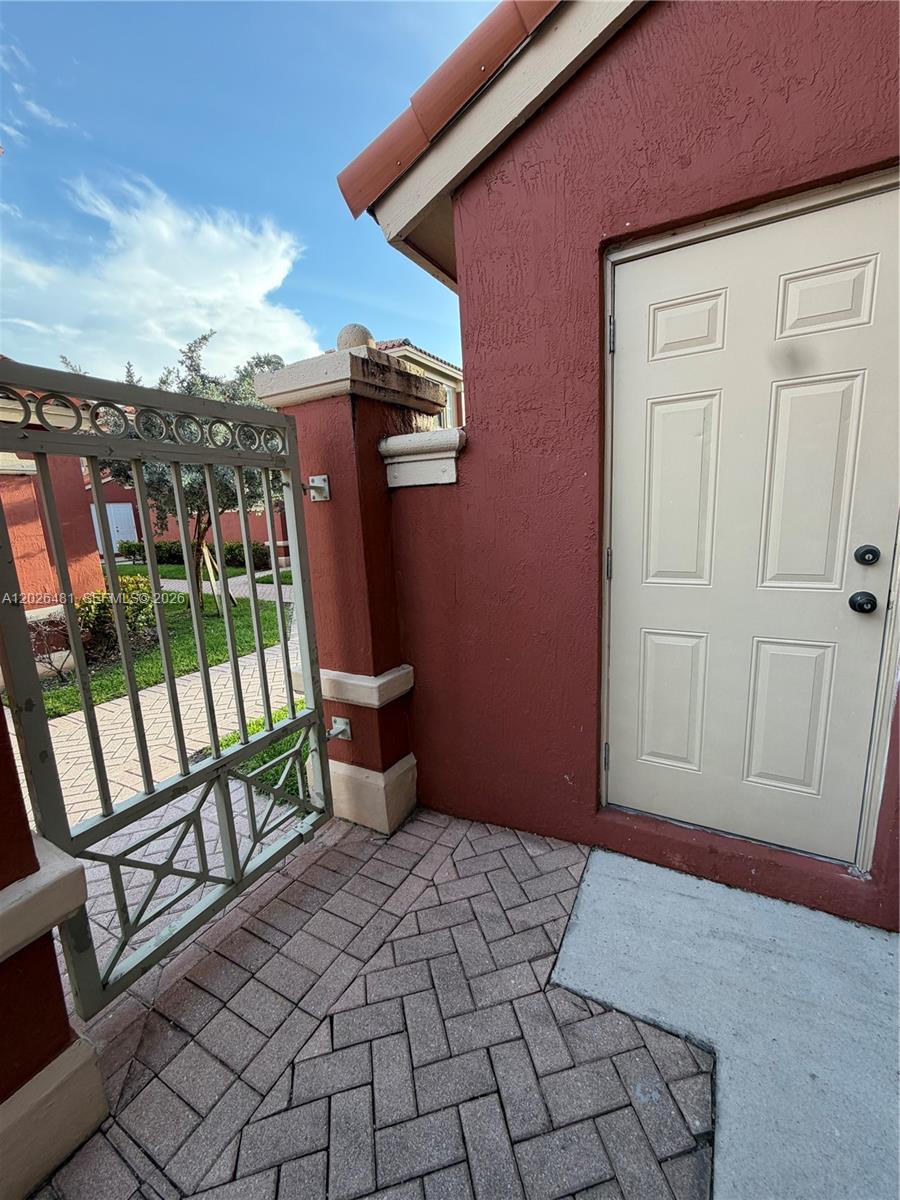 A red stucco wall features a beige door next to a decorative metal gate — 6202 NW 115th Pl # 336, Doral FL 33178, DORAL, FL