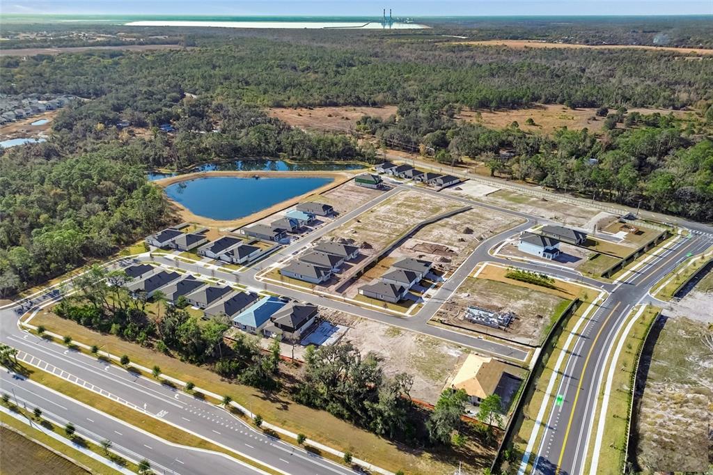 An aerial view shows a new residential housing development under construction near a pond — 4916 MEADOW BAY COURT, WIMAUMA, FL