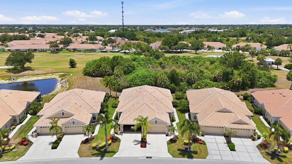 An aerial view shows a row of suburban houses with tan tile roofs and driveways — 1808 SAN TROVASO WAY, VENICE, FL