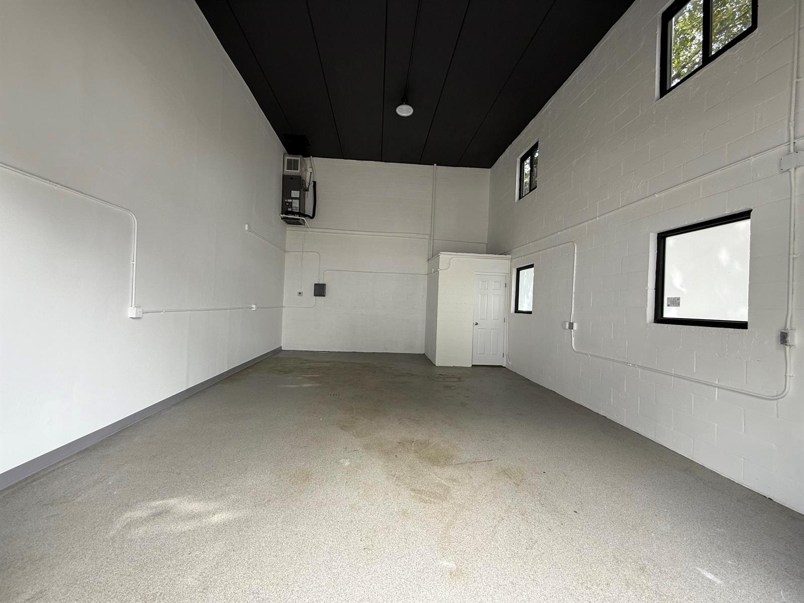 An empty industrial-style room features white painted block walls, a black ceiling, and concrete flooring — 1777 Blount Road # 515, Pompano Beach FL 33069, POMPANO BEACH, FL