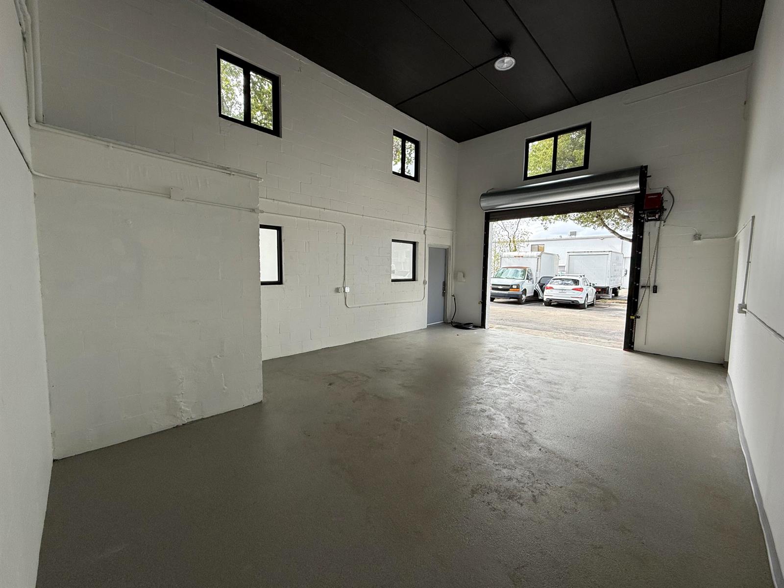 An empty industrial space with white block walls, a black ceiling, and a roll-up door — 1777 Blount Road # 515, Pompano Beach FL 33069, POMPANO BEACH, FL
