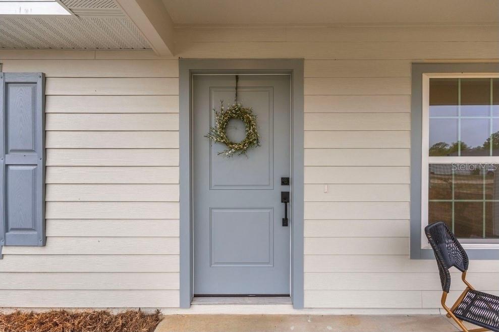 A light blue front door with a wreath is centered on a beige horizontal-sided wall — TBD SEQUOIA LOOP DRIVE, OCKLAWAHA, FL