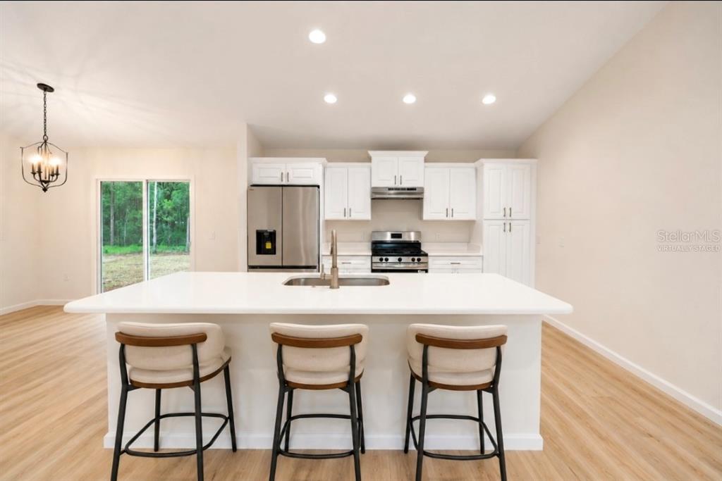 A kitchen with a white island, stainless steel appliances, and light wood-look flooring — TBD SEQUOIA LOOP DRIVE, OCKLAWAHA, FL