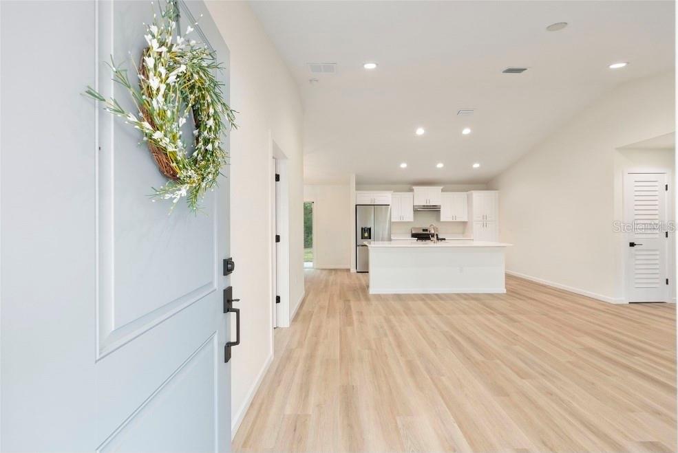 A view from an entryway into an open-concept kitchen with white cabinets and light flooring — TBD SEQUOIA LOOP DRIVE, OCKLAWAHA, FL