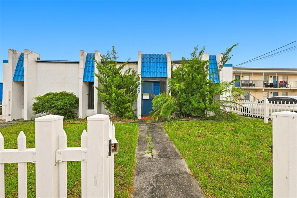A single-story building with white stucco walls, blue tile accents, and a white picket fence — 2508 W TAMPA BAY BOULEVARD, TAMPA, FL