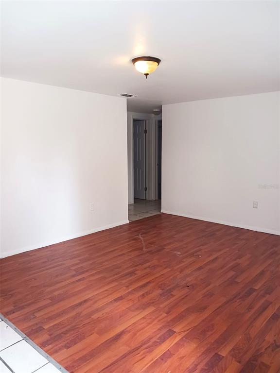 A room with white walls, a flush-mount light fixture, and reddish-brown wood-look flooring — 21377 CAMPBELL DRIVE, BROOKSVILLE, FL