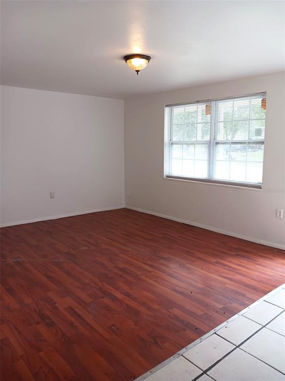 An empty room features wood-look laminate flooring, white walls, a ceiling light, and a window — 21377 CAMPBELL DRIVE, BROOKSVILLE, FL