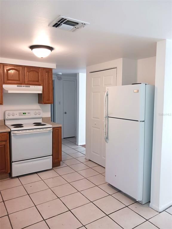 A kitchen features wood cabinets, a white stove, a white refrigerator, and tiled flooring — 21377 CAMPBELL DRIVE, BROOKSVILLE, FL