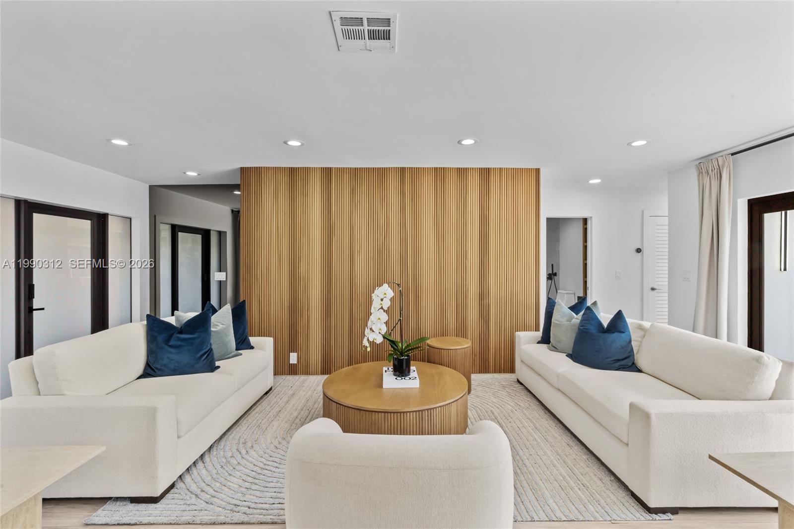 A living room features two white sofas, a round coffee table, and a slatted wood wall — 116 W 1st Ct, Miami Beach FL 33139, MIAMI BEACH, FL