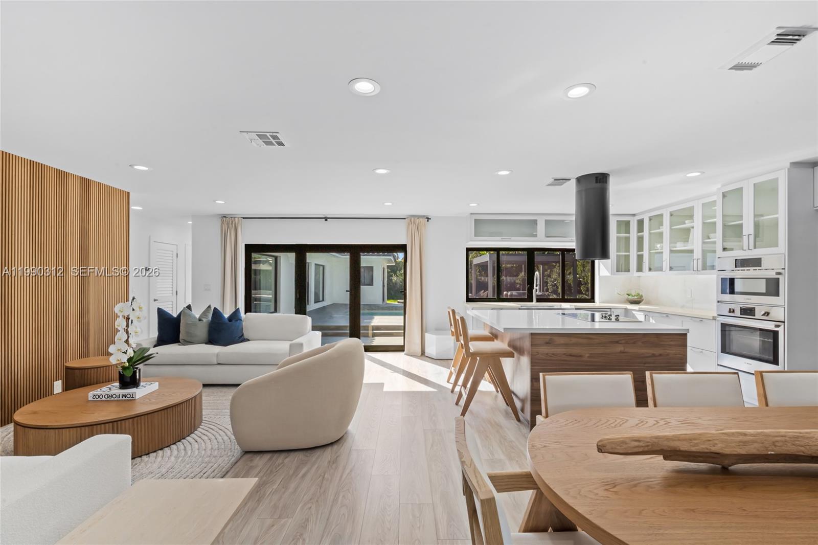 An open-concept living and kitchen area features wood accents, white cabinetry, and sliding glass doors — 116 W 1st Ct, Miami Beach FL 33139, MIAMI BEACH, FL