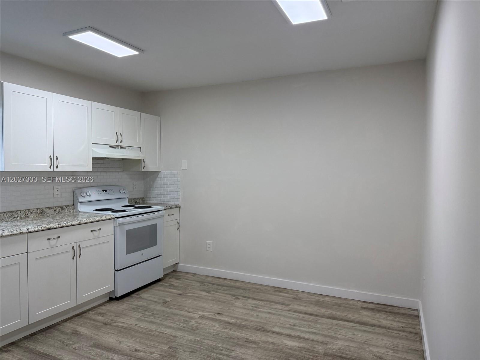 A kitchen features white cabinets, granite countertops, a white stove, and light wood-look flooring — 1580 SW 2nd St # 4, Miami FL 33135, MIAMI, FL