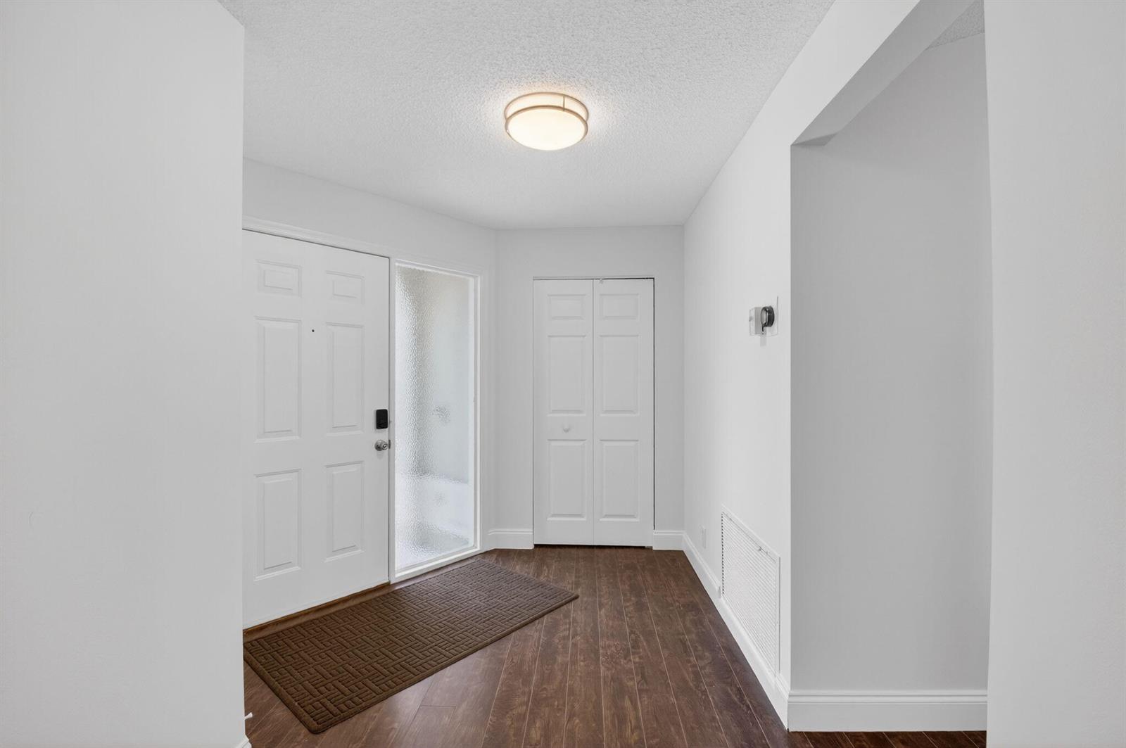 A kitchen features white cabinets, stainless steel appliances, and white countertops over dark wood floors — 6157 Bay Isles Drive, Boynton Beach FL 33437, BOYNTON BEACH, FL