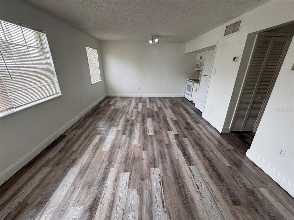 An open-concept living and kitchen area features wood-look flooring and white walls — 5317 CURRY FORD ROAD UNIT O201, ORLANDO, FL