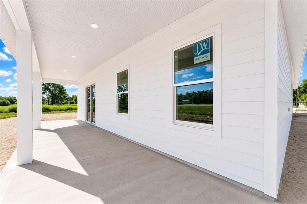 A covered concrete patio features white horizontal siding and two Jeld-Wen windows — 13305 NE 54TH STREET, WILLISTON, FL
