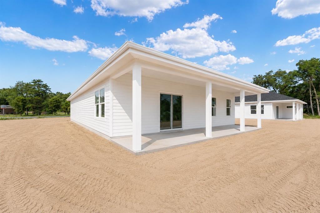 A white house exterior features a covered concrete patio and sliding glass doors — 13305 NE 54TH STREET, WILLISTON, FL