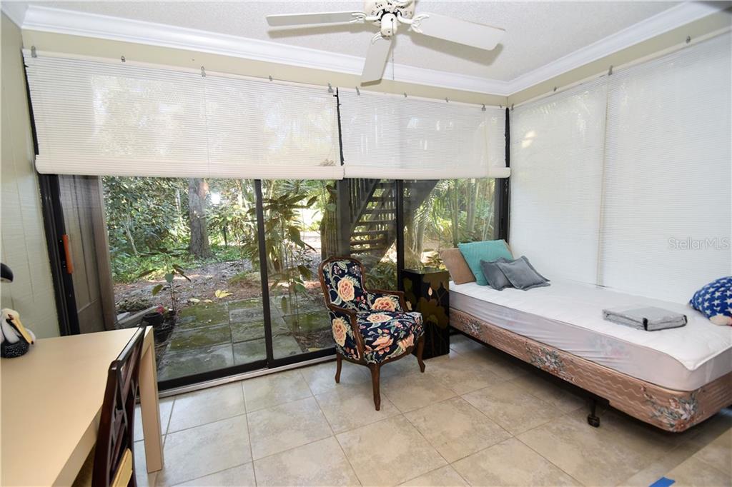 A sunroom with tile floors, a daybed, a floral armchair, and large sliding glass doors — 1716 GLENHOUSE DRIVE UNIT GL324, SARASOTA, FL