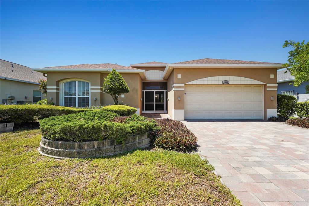A single-story house with a tan stucco exterior, a paved driveway, and a landscaped front yard — 4510 50TH DRIVE W, BRADENTON, FL