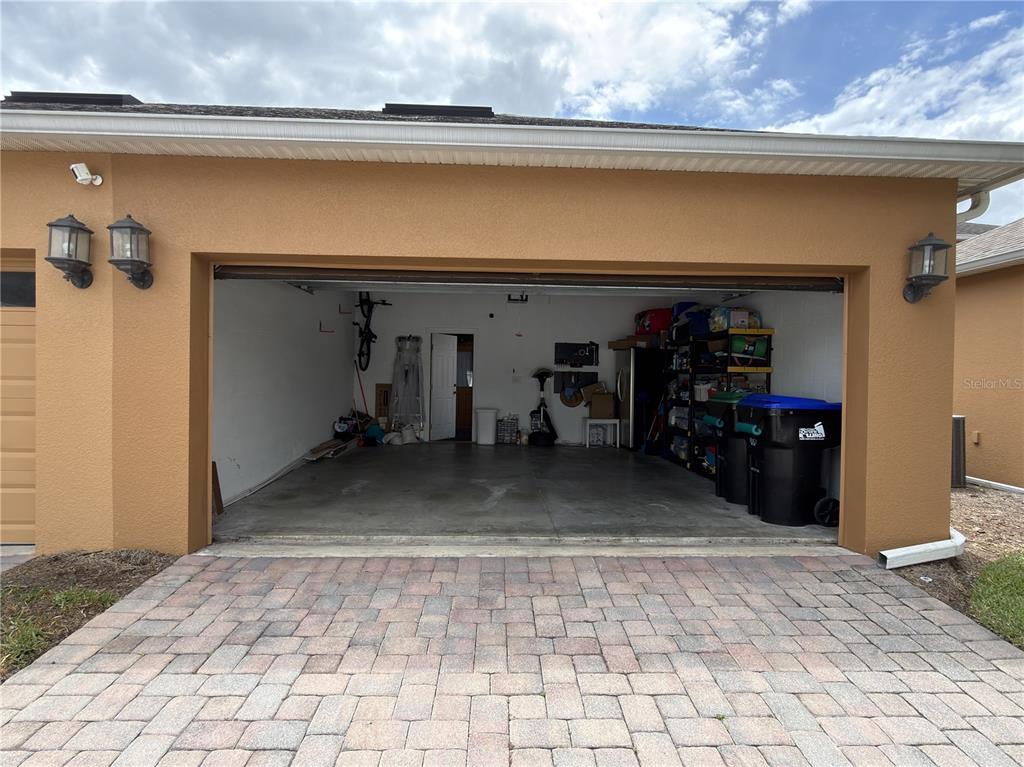 An open garage with a concrete floor, storage shelving, and a door leading inside — 5413 NEW INDEPENDENCE PARKWAY, WINTER GARDEN, FL