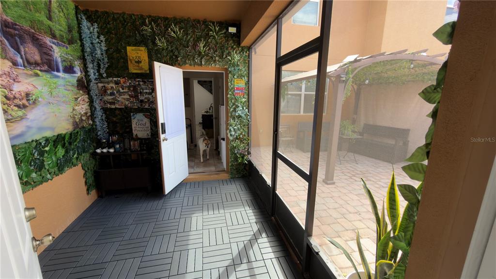 A screened-in patio features gray interlocking floor tiles, a faux-greenery wall, and an outdoor courtyard — 5413 NEW INDEPENDENCE PARKWAY, WINTER GARDEN, FL