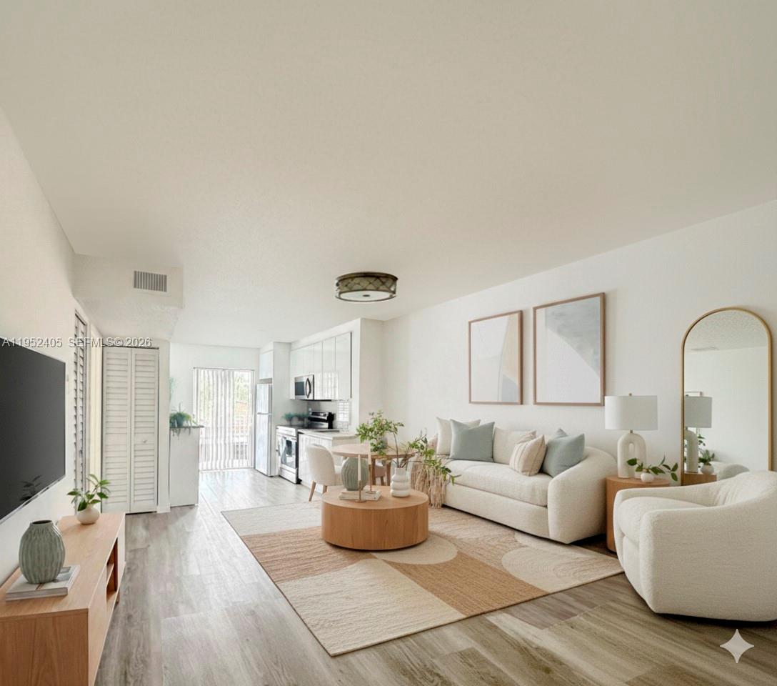 A bright living room features a white sofa, round coffee table, and an open kitchen — 2575 SW 27th Ave # 210, Miami FL 33133, MIAMI, FL