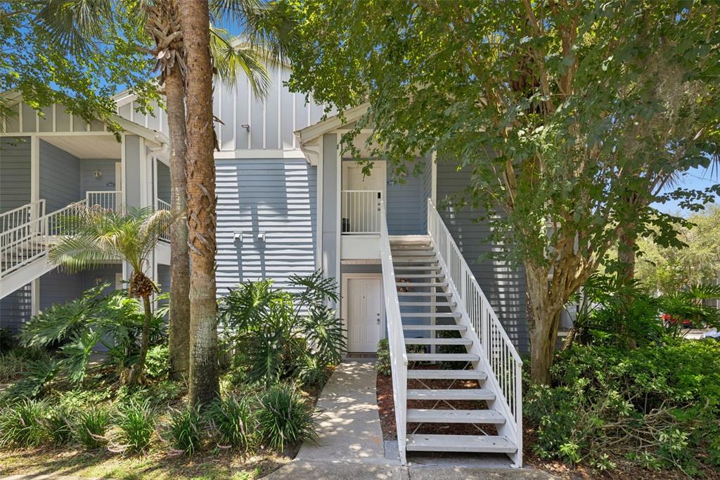 A two-story blue apartment building features an exterior staircase leading to an upper-level entrance — 2532 GRASSY POINT DR UNIT 100, LAKE MARY, FL