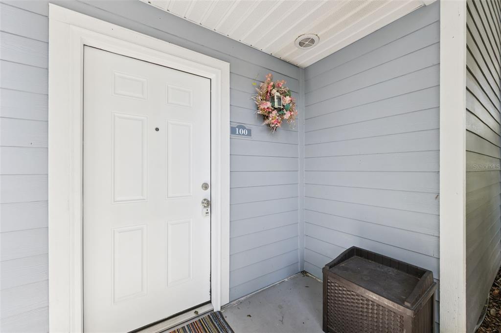 A white front door with a wreath and house number 100 on light blue siding — 2532 GRASSY POINT DR UNIT 100, LAKE MARY, FL