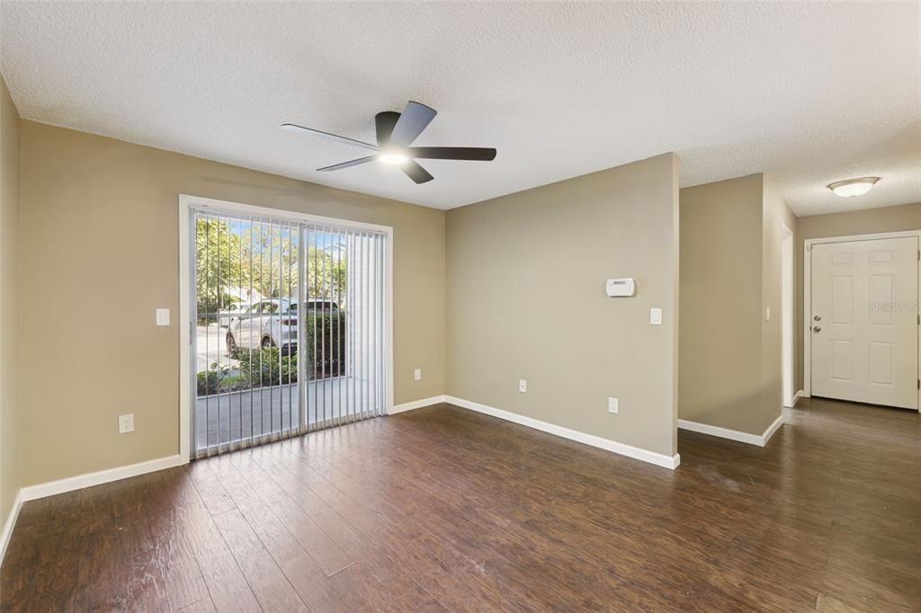 An empty living room with dark wood-look flooring, a ceiling fan, and sliding glass doors — 2532 GRASSY POINT DR UNIT 100, LAKE MARY, FL