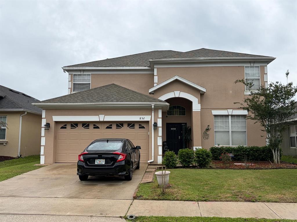 A two-story tan house with a two-car garage and a black sedan parked in front — 852 HARING LANE, MOUNT DORA, FL