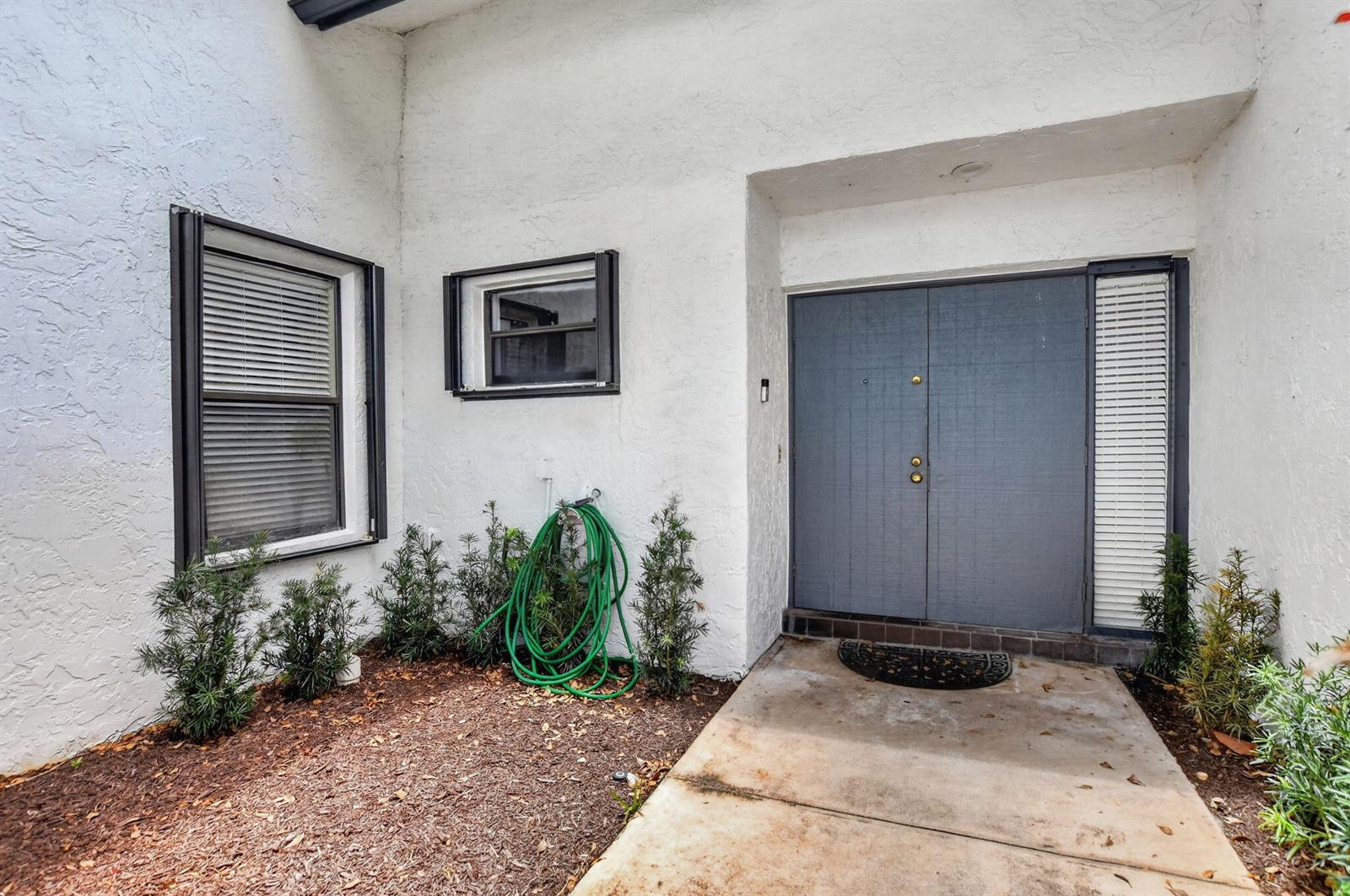 A white stucco house exterior features a double front door, windows, and a garden bed — 7833 San Marcos Place, Boca Raton FL 33433, BOCA RATON, FL
