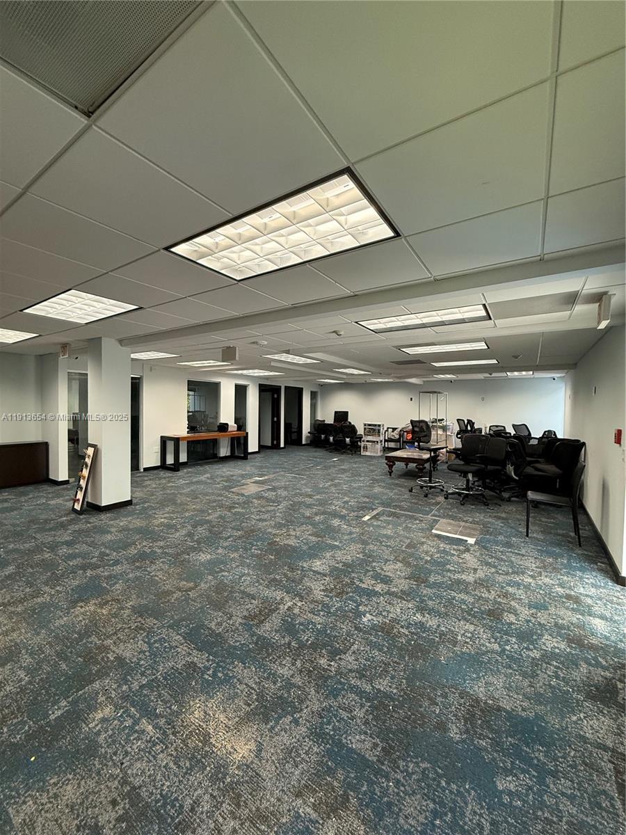 An office space features a patterned carpet, drop ceiling with recessed lighting, and scattered furniture — 9450 SW 72nd St, Miami FL 33173, MIAMI, FL