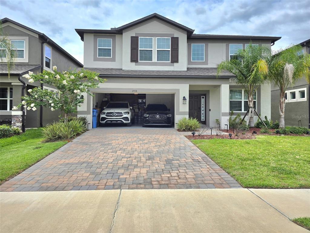 A two-story house with a paved driveway, two parked cars, and a front lawn — 2950 ADAMS CROSS DRIVE, ZEPHYRHILLS, FL