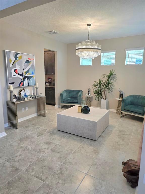 A living room features two teal armchairs, a square coffee table, and a crystal chandelier — 2950 ADAMS CROSS DRIVE, ZEPHYRHILLS, FL
