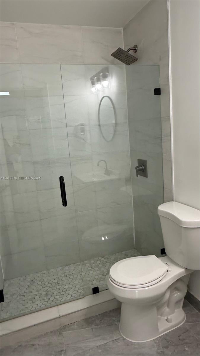 A bathroom features a glass-enclosed shower with a rainfall showerhead and a white toilet — 411 SE 10th St # 3, Hallandale Beach FL 33009, HALLANDALE BEACH, FL