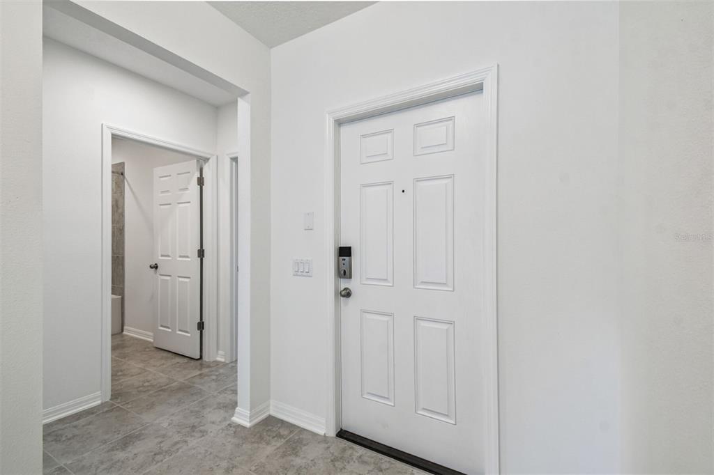 An interior view shows a white front door and an open doorway leading to a bathroom — 12872 CASTLE OAKS DRIVE, HUDSON, FL