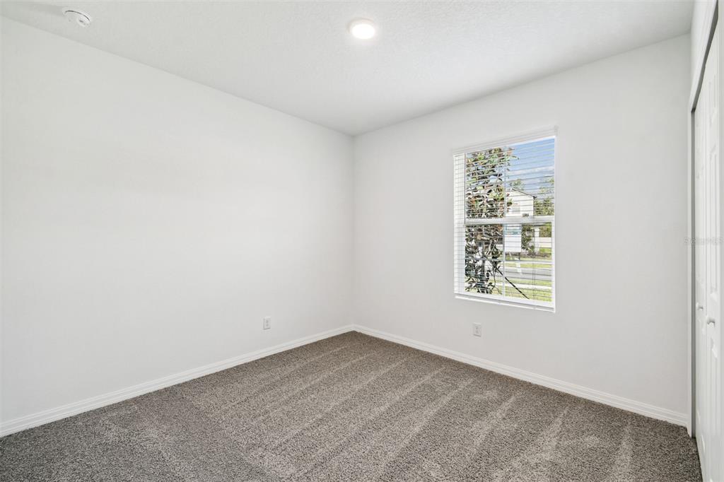 An empty bedroom features white walls, gray carpet, a single window, and a ceiling light — 12872 CASTLE OAKS DRIVE, HUDSON, FL